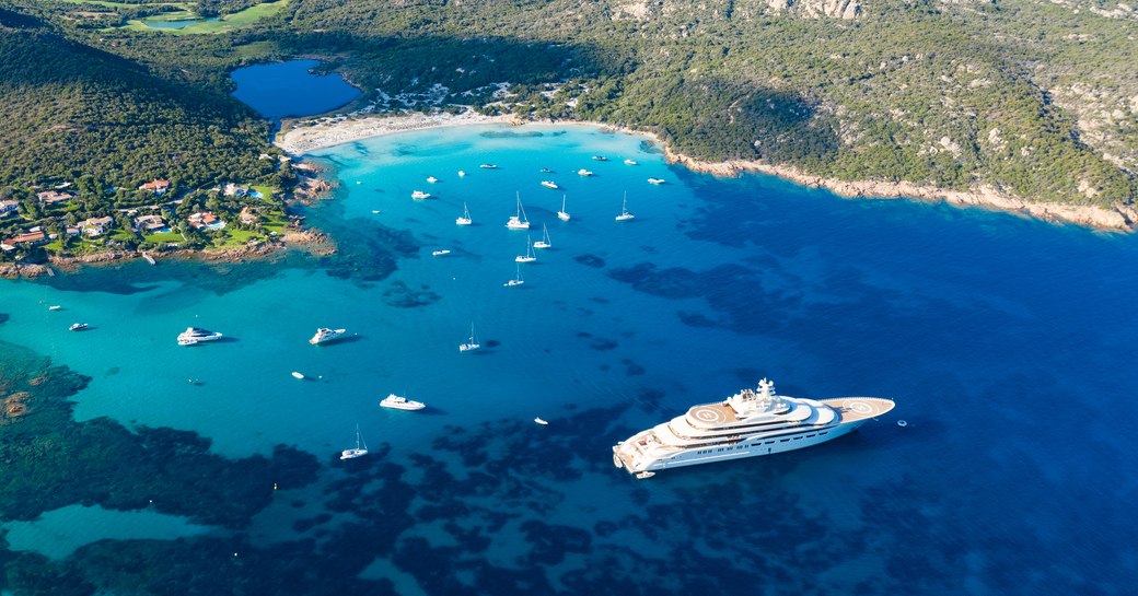 Aerial view of luxury yachts anchored in the turquoise waters of Grande Pevero Beach, Sardinia.