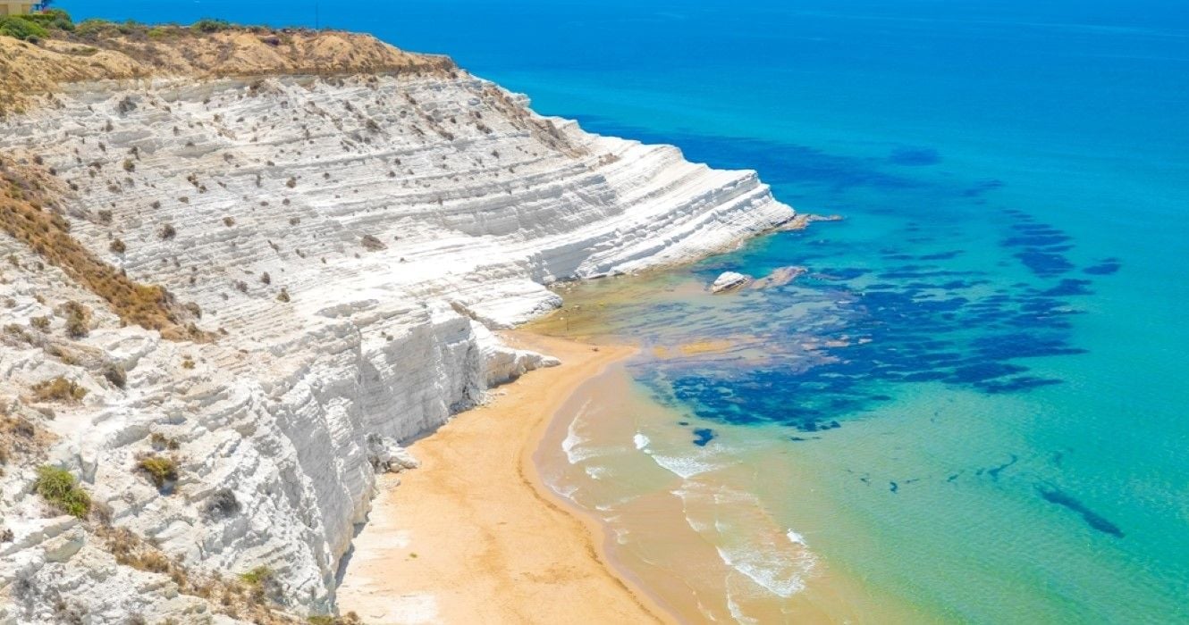 Yacht cruising by the white cliff terraces of Scala dei Turchi, Sicily